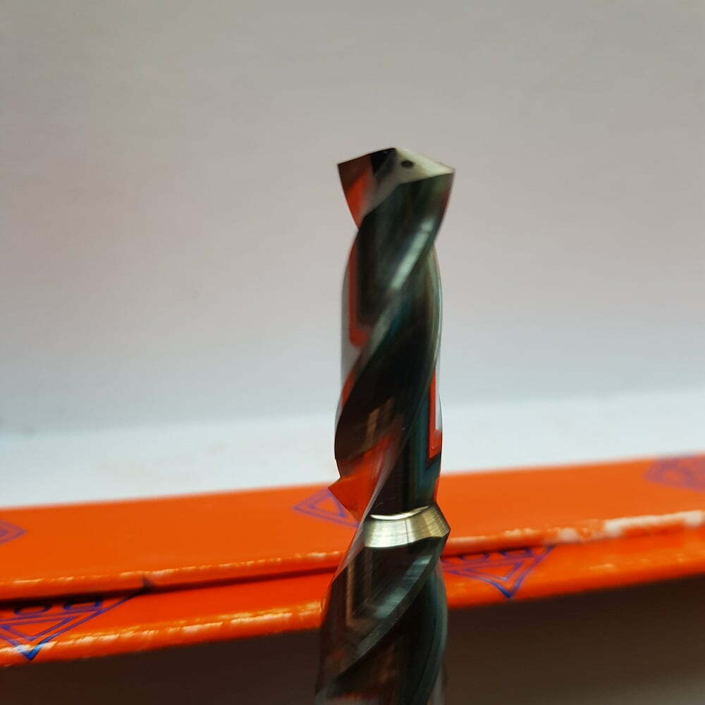 Broca de metal con diseño helicoidal, ideal para perforación en materiales duros, sobre fondo naranja de embalaje.