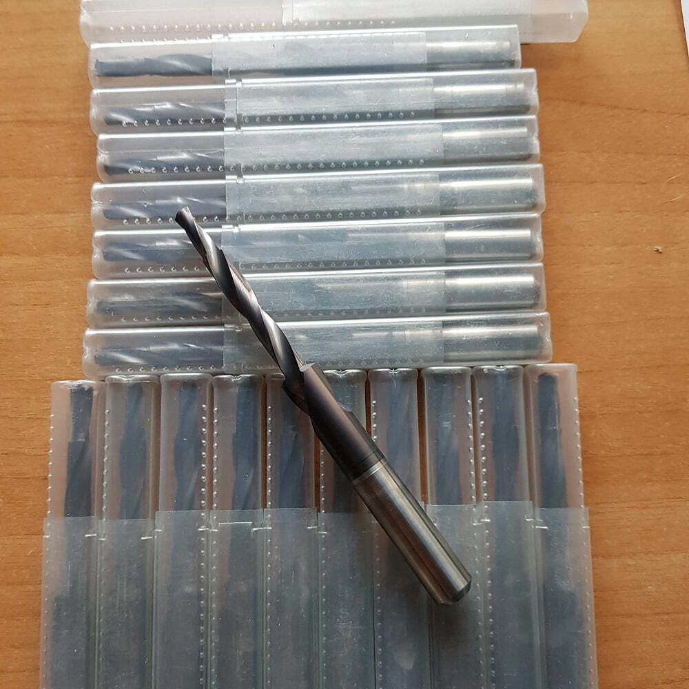 Conjunto de brocas de alta precisión organizadas en estuches transparentes, destacando una broca de metal en primer plano. Ideal para trabajos de mecanizado y carpintería.
