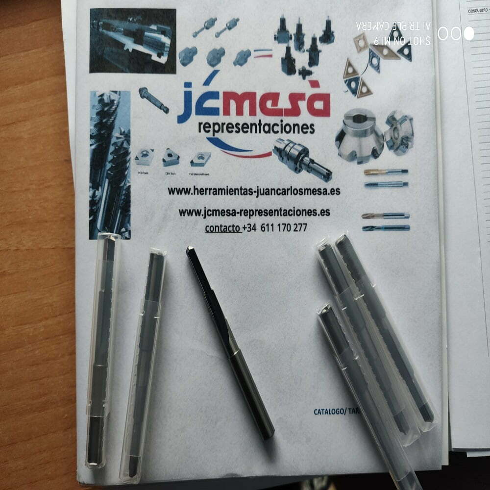 Imagen que muestra herramientas de precisión y accesorios de la empresa J. C. Mesa, incluyendo diversos tipos de brocas y fresas, sobre un fondo con información de contacto y un catálogo.