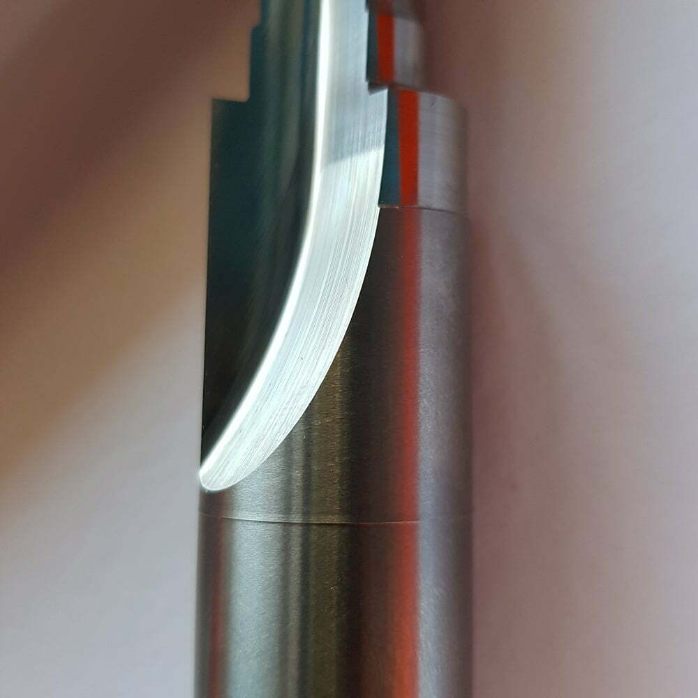Detalle de una herramienta de corte de metal, mostrando la hoja curvada y el acabado pulido en la superficie. Ideal para aplicaciones de mecanizado y fresado.